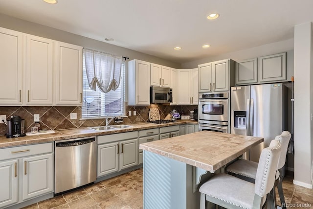 kitchen with sink, stainless steel appliances, white cabinetry, and tasteful backsplash