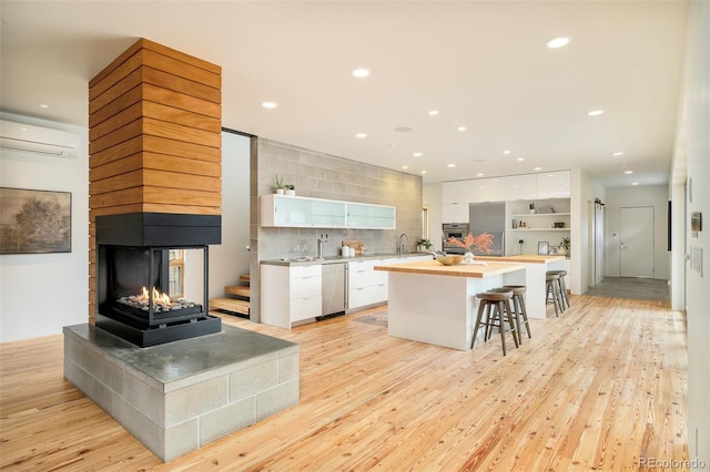 kitchen featuring a wall mounted air conditioner, white cabinets, open shelves, and butcher block countertops