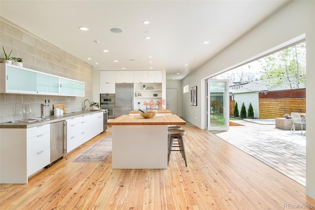 kitchen with light wood finished floors, open shelves, modern cabinets, butcher block countertops, and white cabinetry