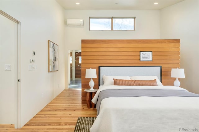 bedroom with recessed lighting, a wall mounted air conditioner, and wood finished floors