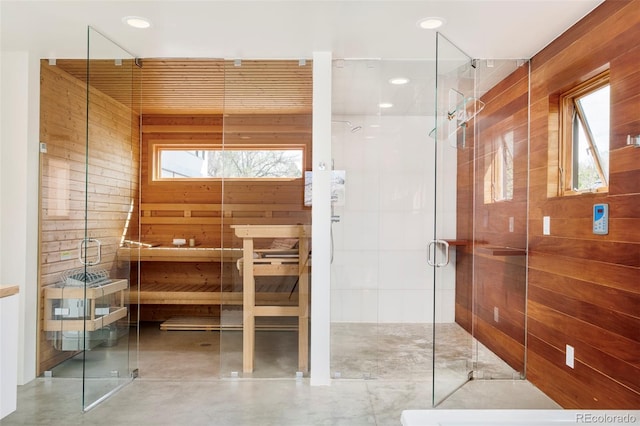 bathroom featuring a stall shower, concrete flooring, a sauna, wood walls, and recessed lighting