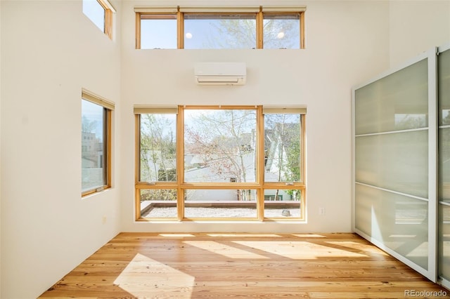 entryway with a wealth of natural light, a high ceiling, and a wall unit AC