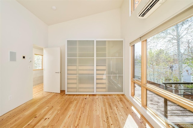interior space with a towering ceiling, wood finished floors, and a wall mounted air conditioner