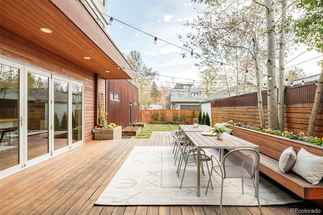 wooden terrace with outdoor dining area and a fenced backyard