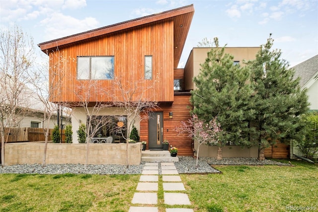 back of house featuring fence and a lawn