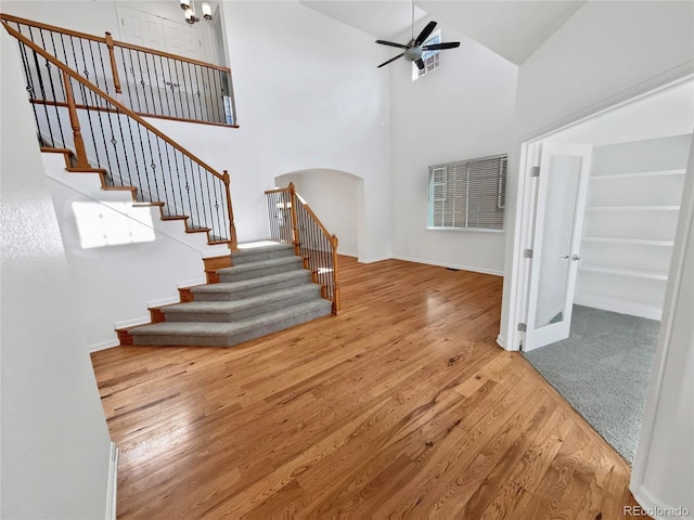 2180 Trailblazer Way, Castle Rock, CO 80109 - unfurnished living room with arched walkways, a ceiling fan, stairway, wood finished floors, and high vaulted ceiling