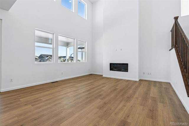 unfurnished living room with a towering ceiling and hardwood / wood-style floors