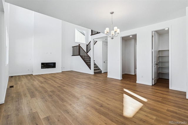 unfurnished living room featuring heating unit, a notable chandelier, and wood-type flooring