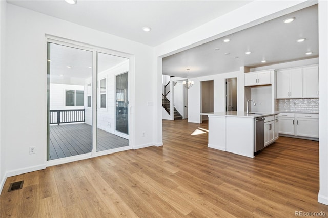 kitchen featuring dishwasher, sink, white cabinets, and light hardwood / wood-style flooring