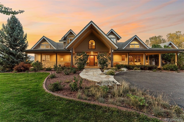 craftsman inspired home with a porch, stone siding, and a front lawn