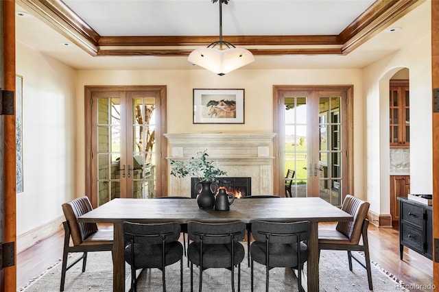 dining room with french doors, ornamental molding, a premium fireplace, and a raised ceiling