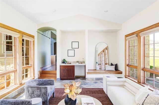 sitting room featuring vaulted ceiling and arched walkways