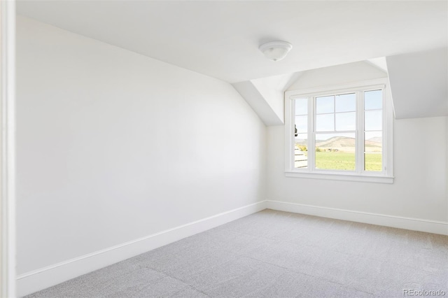 additional living space with lofted ceiling, light carpet, and baseboards