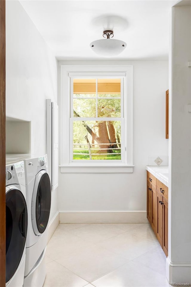 laundry area with washing machine and dryer, baseboards, and light tile patterned floors
