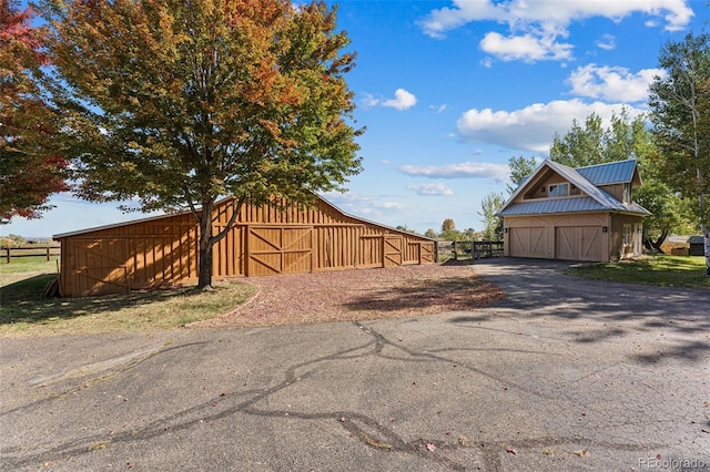 view of asphalt driveway featuring a barn