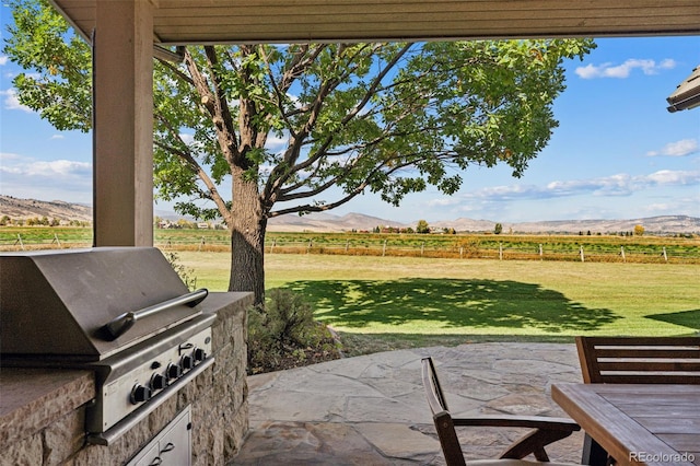 view of patio / terrace with area for grilling, a rural view, and a mountain view