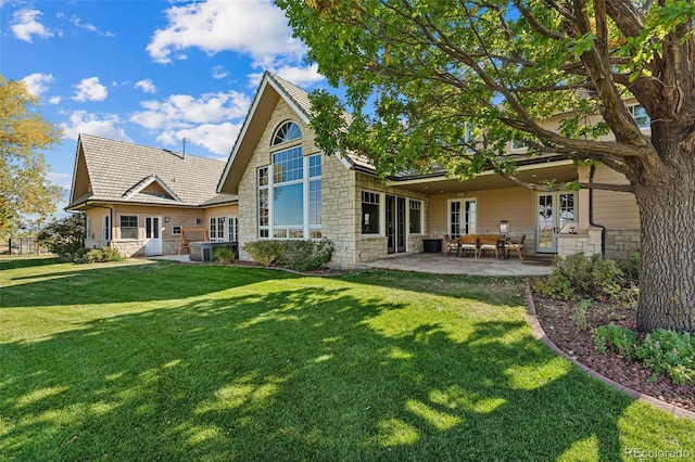 rear view of house featuring stone siding, a lawn, a patio, and central AC unit