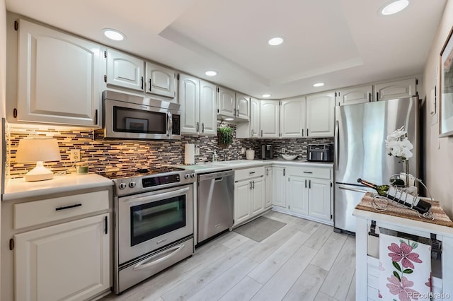 14390 E Marina Dr Unit 403, Aurora, CO 80014 - kitchen featuring appliances with stainless steel finishes, recessed lighting, light countertops, a tray ceiling, and tasteful backsplash