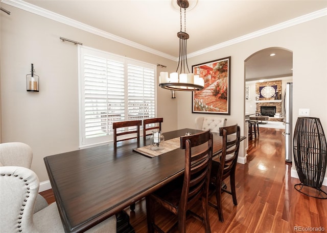 1530 Woodrose Ct, Colorado Springs, CO 80921 - dining area featuring dark wood finished floors, arched walkways, healthy amount of natural light, baseboards, and crown molding