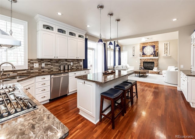 1530 Woodrose Ct, Colorado Springs, CO 80921 - kitchen with appliances with stainless steel finishes, a sink, a breakfast bar, dark wood-style flooring, and a stone fireplace
