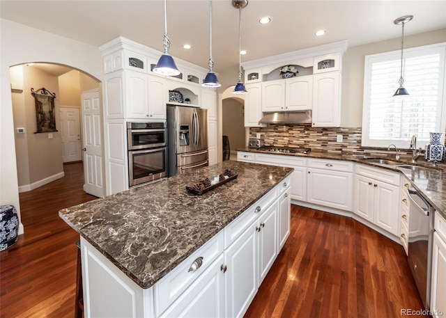 1530 Woodrose Ct, Colorado Springs, CO 80921 - kitchen featuring arched walkways, stainless steel appliances, glass insert cabinets, a center island, and recessed lighting