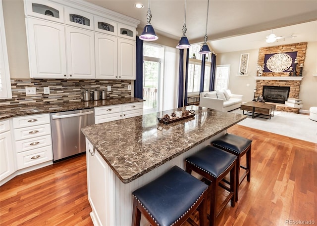 1530 Woodrose Ct, Colorado Springs, CO 80921 - kitchen with stainless steel dishwasher, light wood-style flooring, a kitchen breakfast bar, white cabinetry, and recessed lighting
