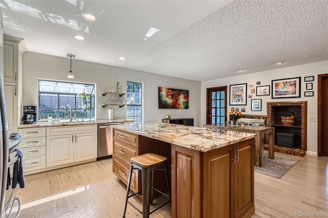 8820 W 80th Dr, Arvada, CO 80005 - kitchen featuring appliances with stainless steel finishes, a center island, a breakfast bar area, light wood-type flooring, and light stone countertops