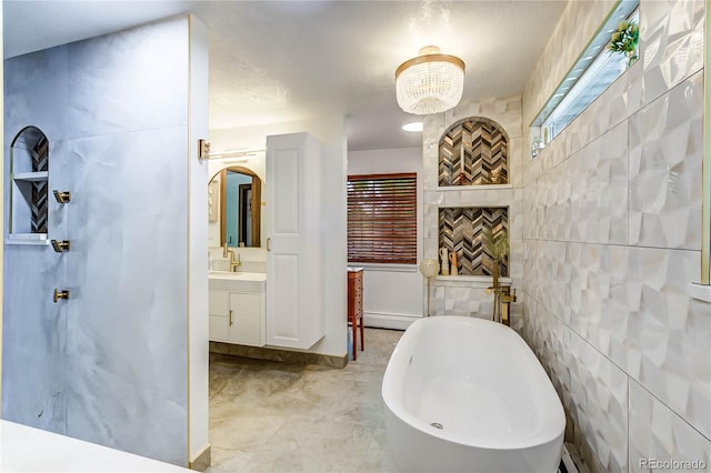 bathroom featuring tile patterned flooring, a tub to relax in, baseboard heating, tile walls, and vanity