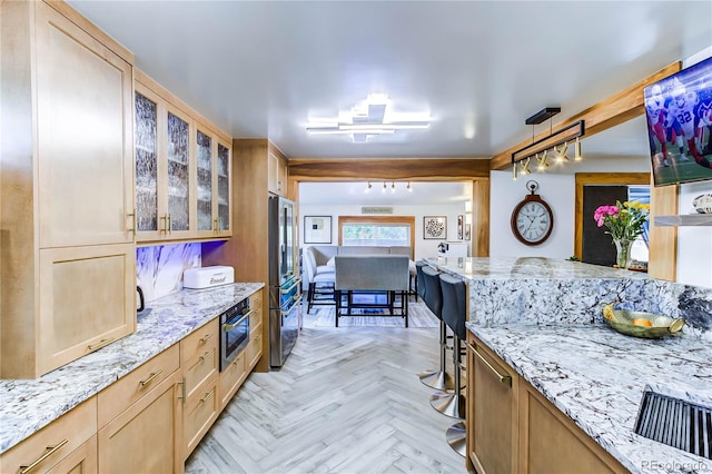 kitchen featuring light parquet floors, stainless steel appliances, light stone countertops, and pendant lighting