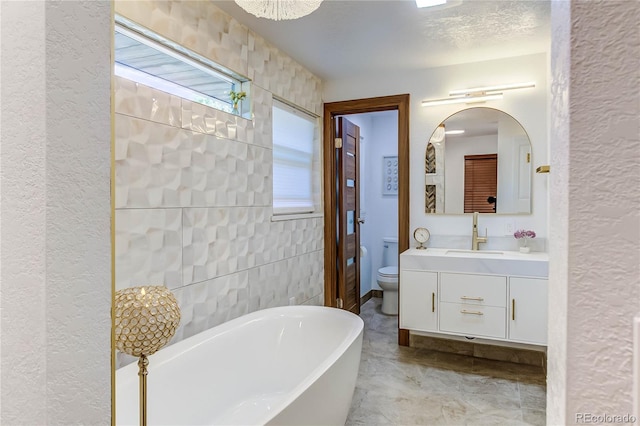 bathroom featuring a textured ceiling, vanity, toilet, a bathtub, and tile patterned floors