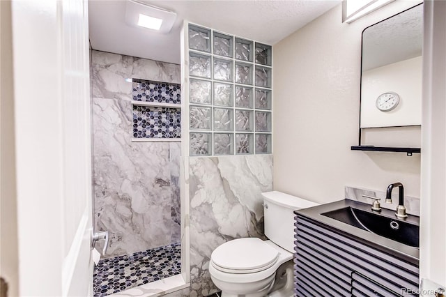 bathroom with tile patterned floors, toilet, a tile shower, tile walls, and vanity