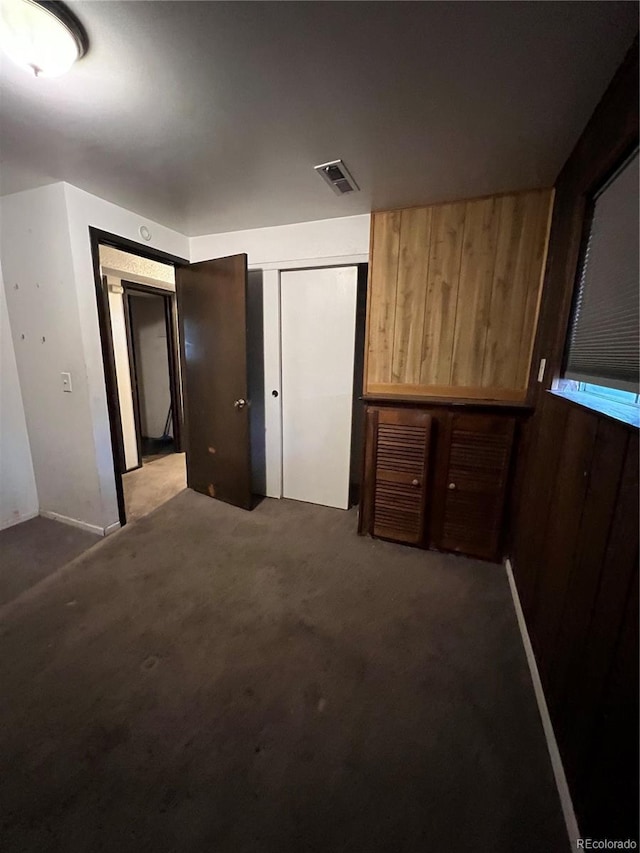 16032 E Floyd Ave, Aurora, CO 80013 - unfurnished bedroom with carpet flooring, wood walls, and a closet
