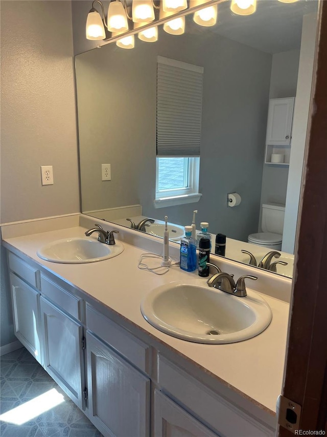 bathroom with toilet, double vanity, and tile patterned flooring