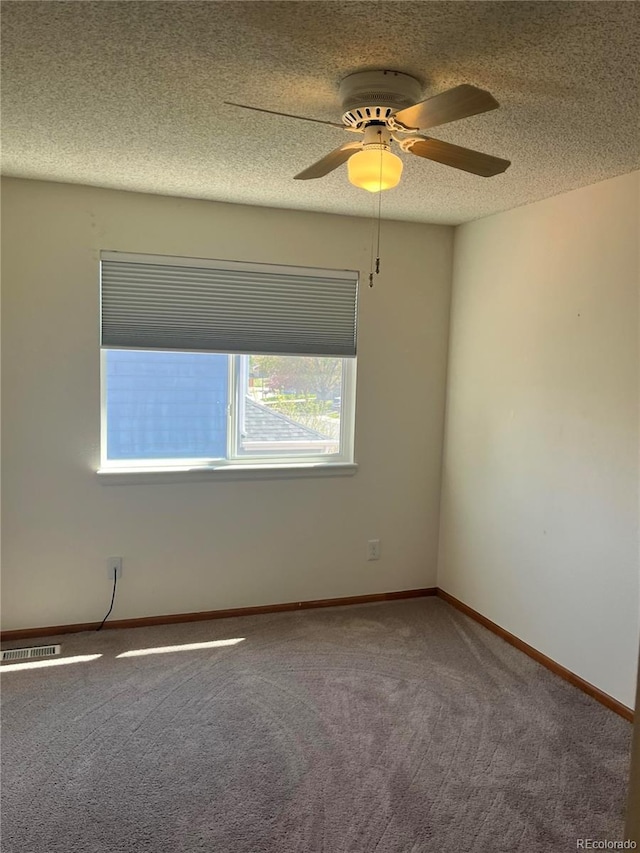 carpeted empty room with a ceiling fan, a textured ceiling, and baseboards