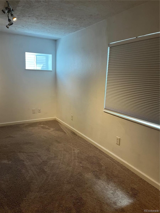 spare room featuring carpet floors, baseboards, and a textured ceiling