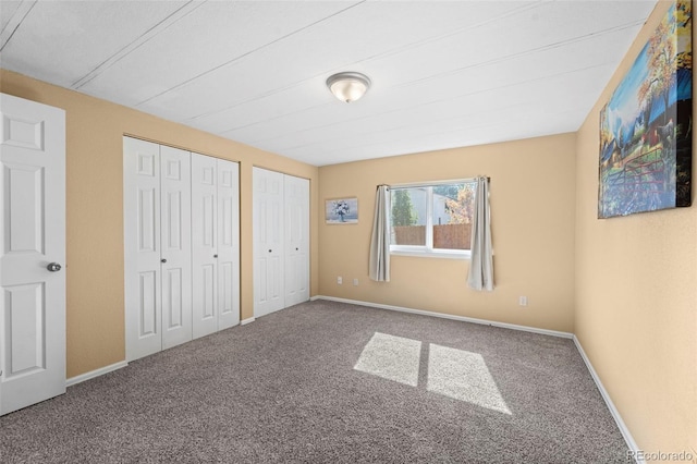 unfurnished bedroom featuring two closets and carpet