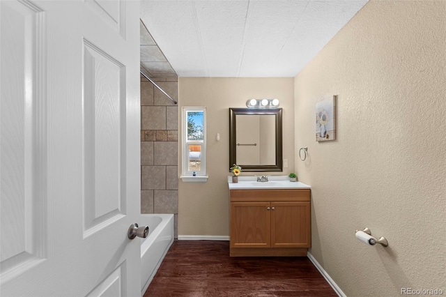 bathroom featuring vanity, tiled shower / bath, a textured ceiling, and wood-type flooring