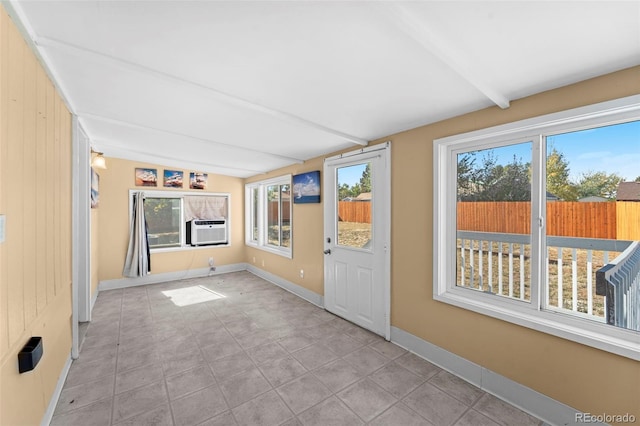 unfurnished sunroom with beam ceiling, cooling unit, and a healthy amount of sunlight