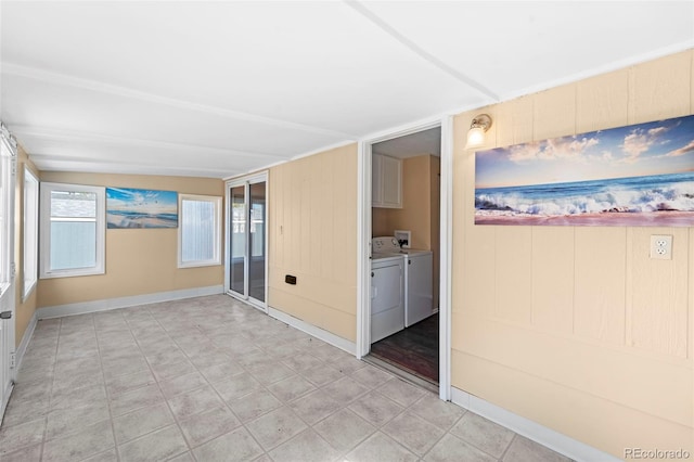 unfurnished room featuring wood walls, a healthy amount of sunlight, and washing machine and clothes dryer