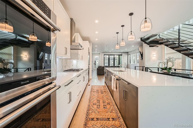 427 Milwaukee St, Denver, CO 80206 - kitchen with decorative backsplash, light countertops, wall chimney exhaust hood, white cabinets, and appliances with stainless steel finishes