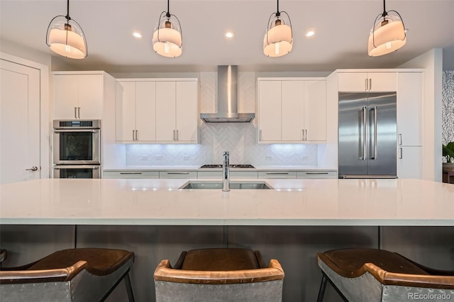 427 Milwaukee St, Denver, CO 80206 - kitchen featuring wall chimney range hood, decorative light fixtures, appliances with stainless steel finishes, and tasteful backsplash