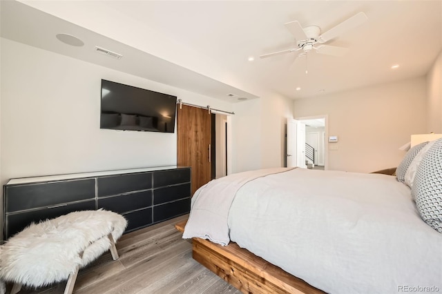 427 Milwaukee St, Denver, CO 80206 - bedroom with ceiling fan, a barn door, recessed lighting, wood finished floors, and visible vents