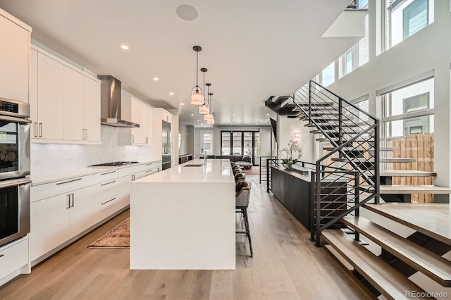 427 Milwaukee St, Denver, CO 80206 - kitchen featuring gas stovetop, white cabinets, wall chimney exhaust hood, and a wealth of natural light