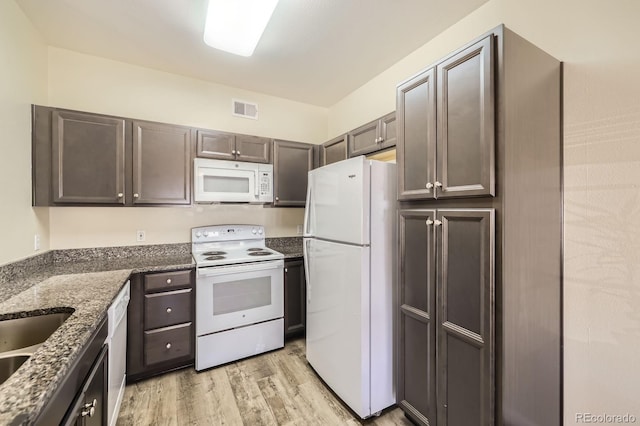 1148 Opal St Unit 101, Broomfield, CO 80020 - kitchen featuring white appliances, light wood-style floors, dark stone counters, a sink, and dark brown cabinetry