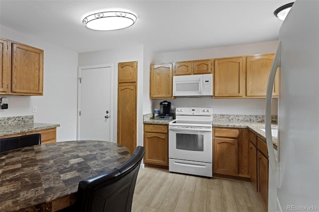 kitchen with white appliances, light wood-style floors, light stone counters, and brown cabinets