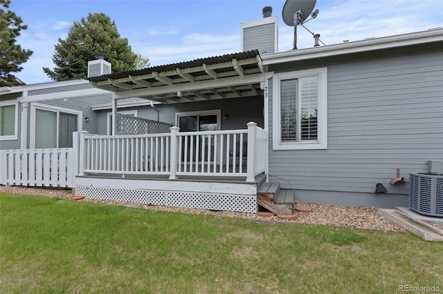 rear view of property featuring a chimney, central AC unit, a lawn, and a deck