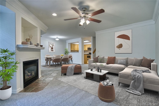 930 Button Rock Dr Unit 29, Longmont, CO 80504 - carpeted living room featuring ornamental molding, ceiling fan, stone finish flooring, a glass covered fireplace, and recessed lighting