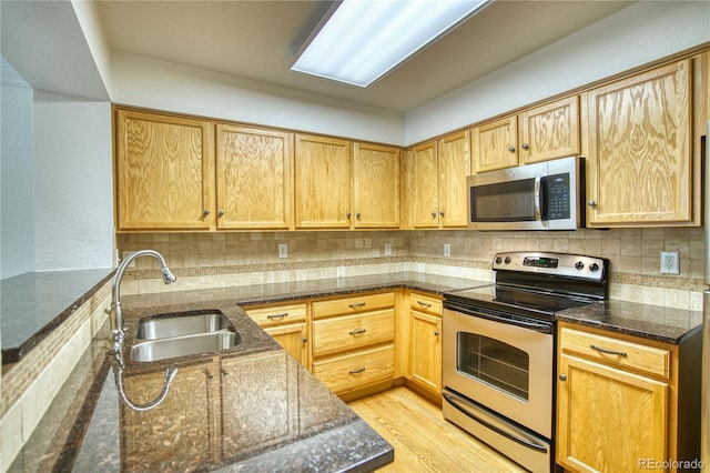 930 Button Rock Dr Unit 29, Longmont, CO 80504 - kitchen featuring appliances with stainless steel finishes, dark stone countertops, light wood-style floors, and decorative backsplash