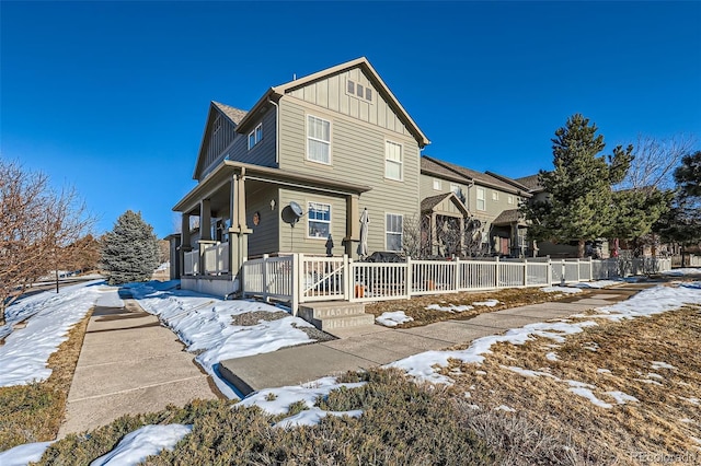 view of front of property with board and batten siding, a porch, and fence