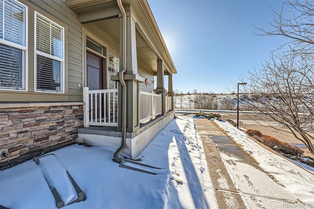 snow covered property with covered porch